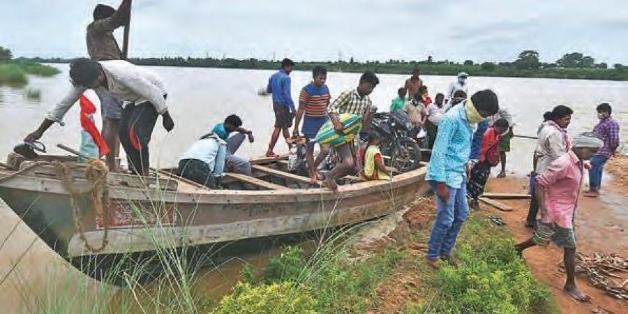 As the road leading to Pamula Lanka is submerged in water, villagers use a mechanised boat to go to the other side of a flooded stream near Vijayawada.