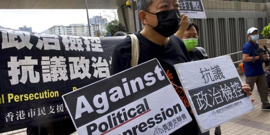 Pro-democracy activist Lee Cheuk-yan, center, holds placards as he arrives at a court in Hong Kong.