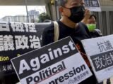 Pro-democracy activist Lee Cheuk-yan, center, holds placards as he arrives at a court in Hong Kong.